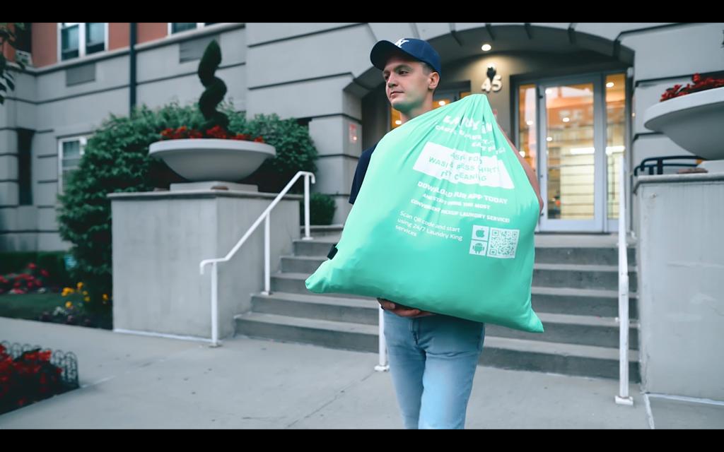 A Laundry King driver collecting a customer's laundry bag at their door in Brooklyn