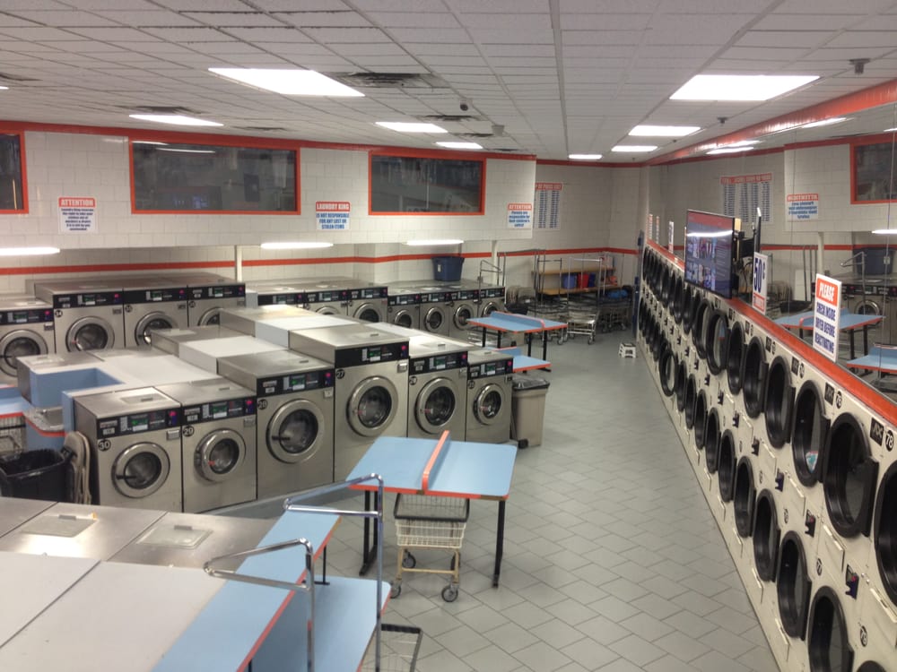 Washing machines and big-screen TVs on the wall of the Laundry King laundromat in Brooklyn